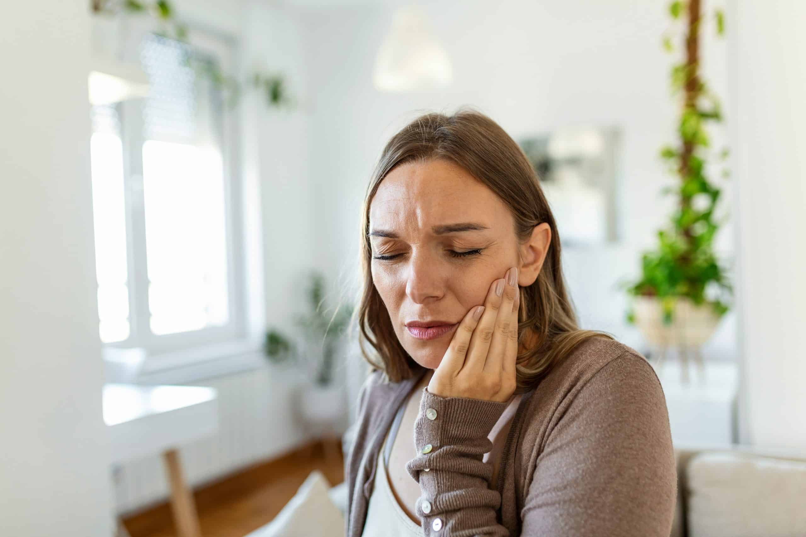 a women holding her jaw in a sore motion