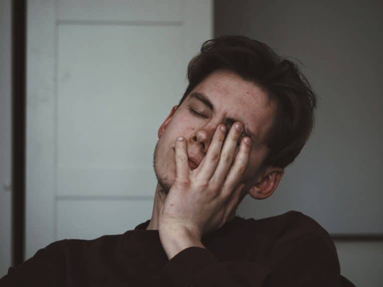 A photo of a man with a headache and his hand to his head in pain