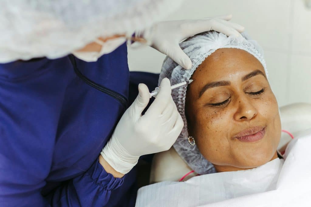 A Women Getting Botox Done To Her Temples By A Medical Professional