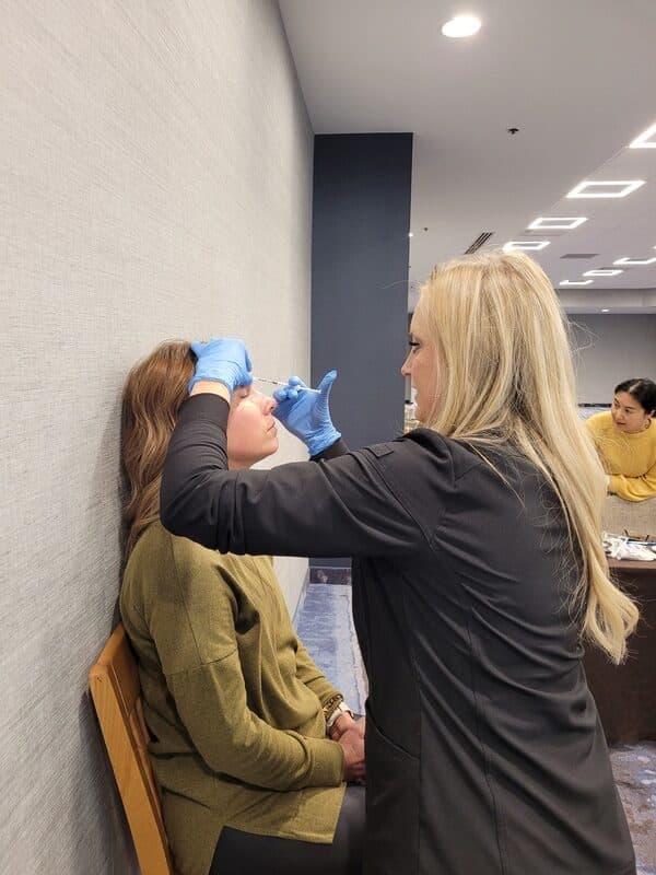 Medical Professional Practicing An Injection Technique On A Seated Model During Hands-On Aafe Tmj Training.
