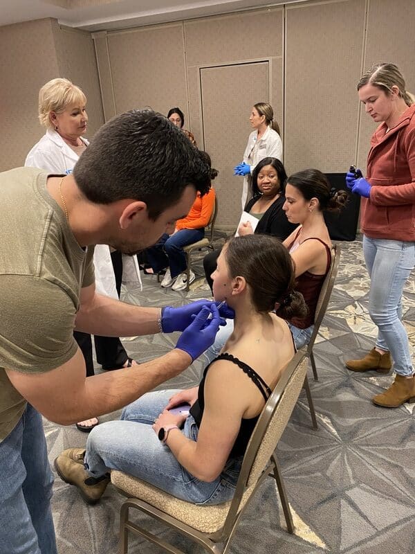 Clinician Practicing A Jaw-Area Injection On A Seated Model During An Aafe Hands-On Tmj Course.