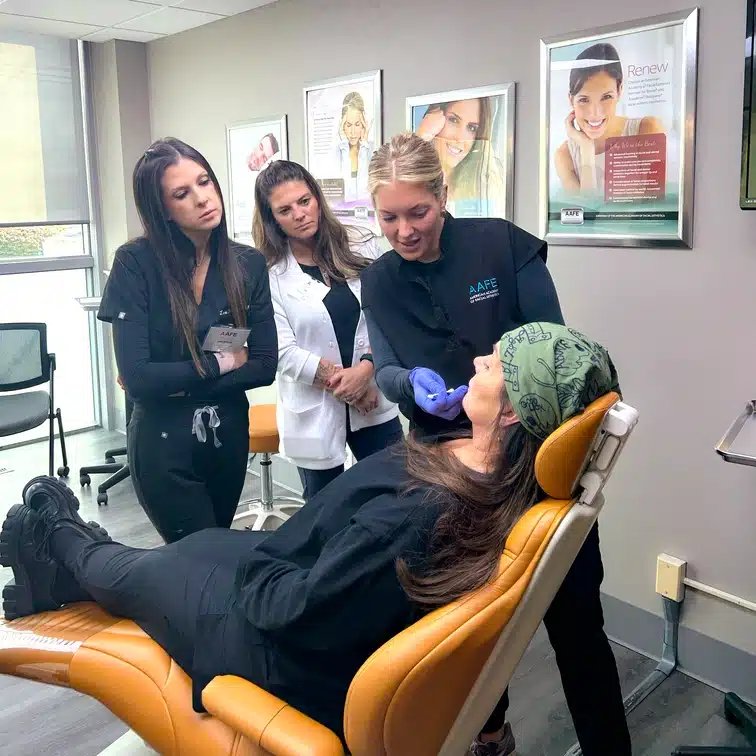 AAFE instructor demonstrating a hands-on facial aesthetics procedure on a patient for trainees.