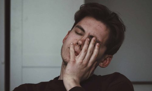 A Photo Of A Man With A Headache And His Hand To His Head In Pain