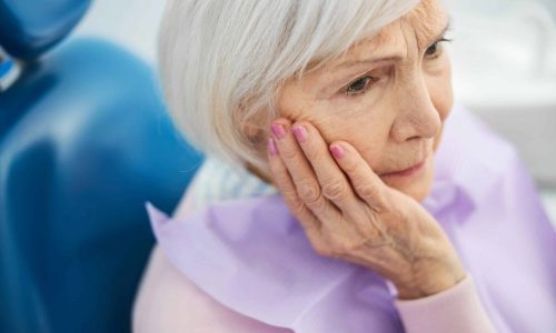 A Women In A Dental Office With Her Hand On Her Jaw In Pain Waiting For Dental Botox